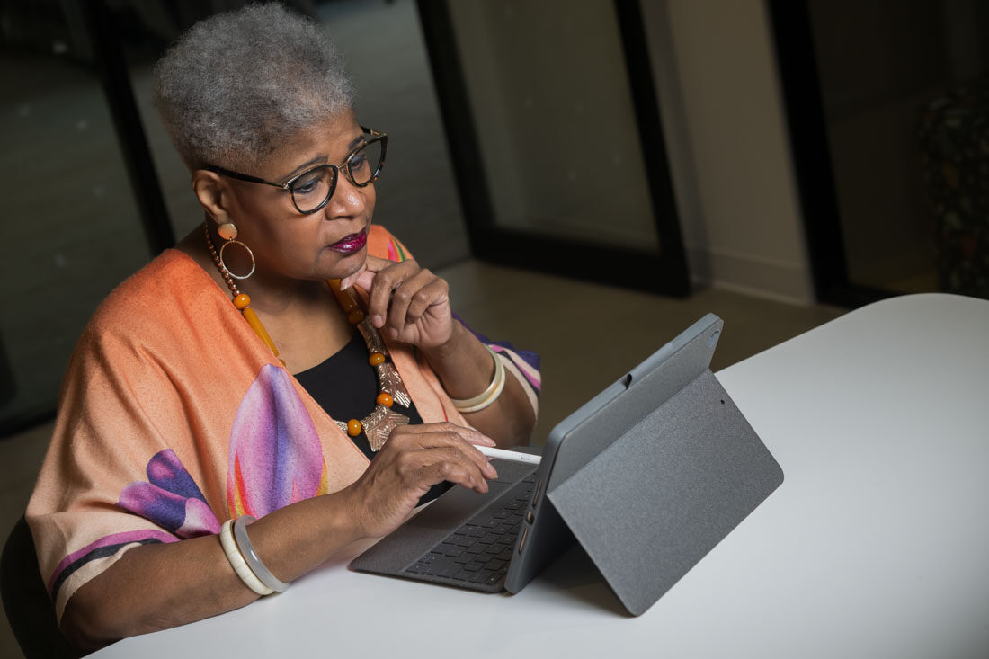 audrey wiggins working at tablet wearing purple and orange wrap.